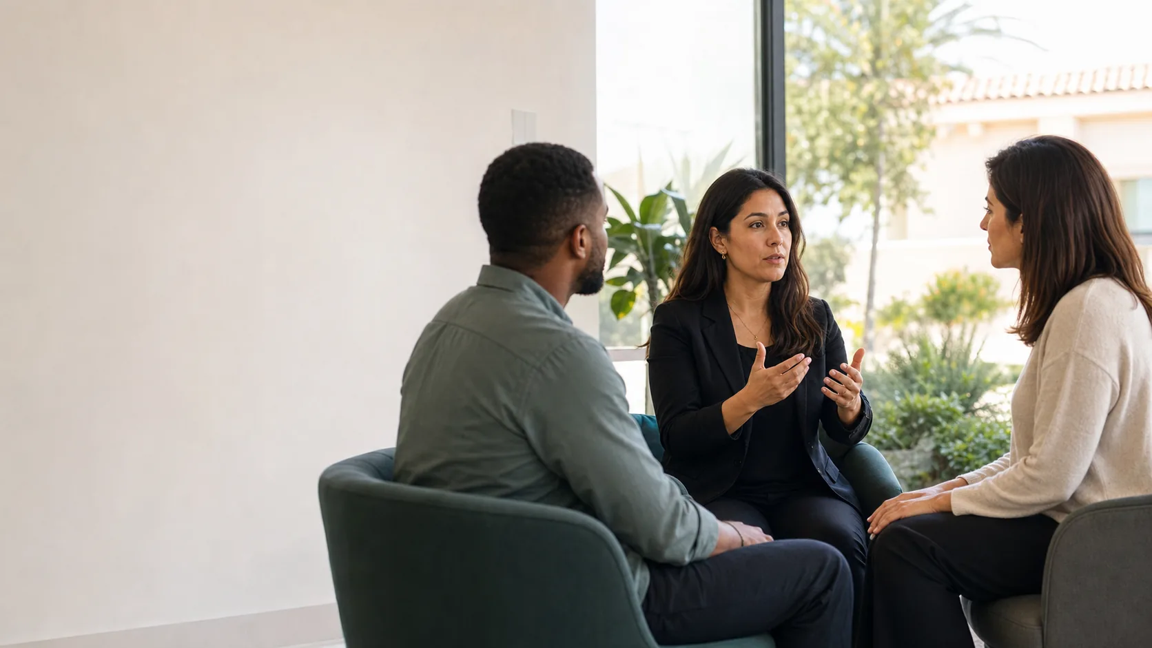 Three diverse adults in a bright office having a natural conversation with an ASL interpreter
